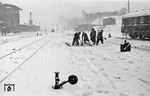 Schneetreiben oder nicht: Die Weichenreiniger im Bahnhof Hamburg-Langenfelde geben ihr bestes. Rechts steht wohl einer der 20 DSG-Wagen Schürzenwagen der Bauart WL4ü-50.  (27.02.1958) <i>Foto: Walter Hollnagel</i>