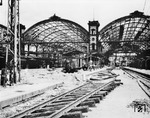 Blick in den kriegszerstörten Münchener Hauptbahnhof, dessen Bahnhofshalle später abgerissen wurde. Auf das Stadtgebiet Münchens wurden im Zweiten Weltkrieg rund 450 Luftminen, 61.000 Sprengbomben, 142.000 Flüssigkeitsbrandbomben und 3.316.000 Stabbrandbomben abgeworfen. Hierbei wurden rund 90 % der historischen Münchener Altstadt zerstört. Das gesamte Stadtgebiet wies einen Zerstörungsgrad von rund 50 % seines Gebäudebestandes auf. Durch die alliierten Luftangriffe wurden rund 300.000 Einwohner obdachlos, weil 81.500 Wohnungen ganz oder teilweise zerstört worden waren. (05.1945) <i>Foto: Pressefoto ACME</i>