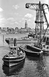 Blick vom Fährkanal über die Elbe auf den Michel. Ein Schleppdampfer und eine offene Schute ohne Antrieb, mit der Massengüter im Hafen etwa Kohle für die Schiffe transportiert wurde, bestimmen die Szene. (1949) <i>Foto: Walter Hollnagel</i>