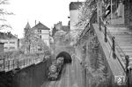 Man muss schon genau hinsehen, aber hier verlässt tatsächlich eine Doppeltraktion mit 38 1869 und 38 3395 vor P 2365 das Westportal des Schloßbergtunnels. Kurioses am Rande: Links neben diesem Einschnitt verläuft sichtbar der „Obere faule Pelz“, daneben der hier nicht sichtbar der „Untere faule Pelz“ mit dem Stadtgefängnis. In den Straßen mit dem besagten "faulen Pelz" (die es im übrigen nur in Heidelberg gibt) lebten keine Faulpelze - es war auch kein Spitzname für die dort einsitzenden Gefängnisinsassen - sondern hier wirkten eigentlich fleißige Handwerker, nämlich Gerber. Nach deren Wegzug im 17. Jahrhundert wurde dem Graben, aus dem die Gerber das Wasser entnahmen, kein Frischwasser mehr zugeführt. In der Folge begann es an zu faulen und bildete schließlich ein dicke Schimmelschicht - den "Pelz". Das Gelände unterhalb des Grabens hieß von nun an "Untere faule Pelz", das darüber der "Obere faule Pelz". Obwohl der Graben längst zugschüttet ist, blieb der Name erhalten. (30.04.1955) <i>Foto: Helmut Röth</i>