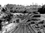 Das in unmittelbarer Nähe zum Bw Köln-Betriebsbahnhof (im Hintergrund) gelegene Bw Köln Gereon führte eher ein Schattendasein. Es lag im tieferliegenden Dreieck der Zufahrtsgleise aus Köln-Süd, -Nippes und -Ehrenfeld. Der ursprünglich vorhandene Ringlokschuppen wurde im Zweiten Weltkrieg zerstört. Auf den verbliebenen Freiständen wurden noch bis in die 1960er Jahren Dampfloks für den Einsatz im nahen Eilgutbahnhofs Gereon abgestellt. Der Schnellzug im Hintergrund fährt von Köln Hbf kommend um das Gelände des Bbf herum in Richtung Köln-West auf die linke Rheinstrecke. Die E 10 wird gleich die Streckengleise aus Köln-Nippes bzw. -Ehrenfeld überqueren. (1966) <i>Foto: Fischer</i>