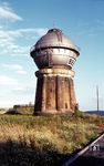 Der Bebraer Wasserturm der Bauart Klönne wurde 1910 zur Versorgung der Lokomotiven fertiggestellt. Das Bauwerk ist ein kegelförmiger Turmunterbau aus Mauerwerk mit integrierten Mauerwerksstützen zur Lastaufnahme, darüber ein aufgesetzter Stahlbehälter mit einem gurtungsähnlichen, umlaufenden Wandelgang für Wartungsarbeiten am Behälter. Auf dem Turm befindet sich der Wasserbehälter mit ca. 500 Kubikmetern Größe. Das Wasser wurde der Fulda entnommen. Nach dem Ende des Dampfbetriebs drohte 1984 der Abriss des Wasserturms. Die Stadt Bebra übernahm 1985 den Turm von der Bahn und sanierte ihn. Heute ist er ein geschütztes Industriedenkmal und Wahrzeichen der Stadt Bebra.  (1974) <i>Foto: Dr. Steinke</i>